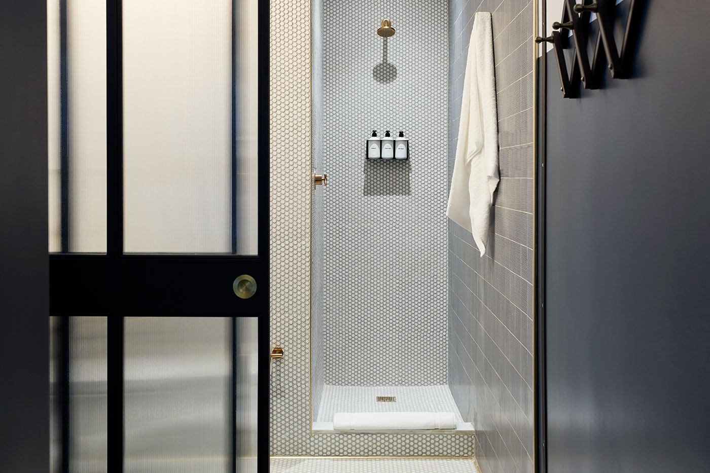 A modern bathroom shower with tiled walls, a shower head, and towels.