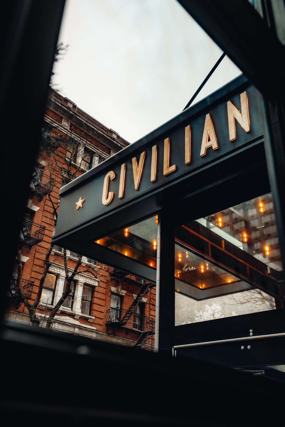 a close-up of a building's awning with the word 'CIVILIAN' in gold letters