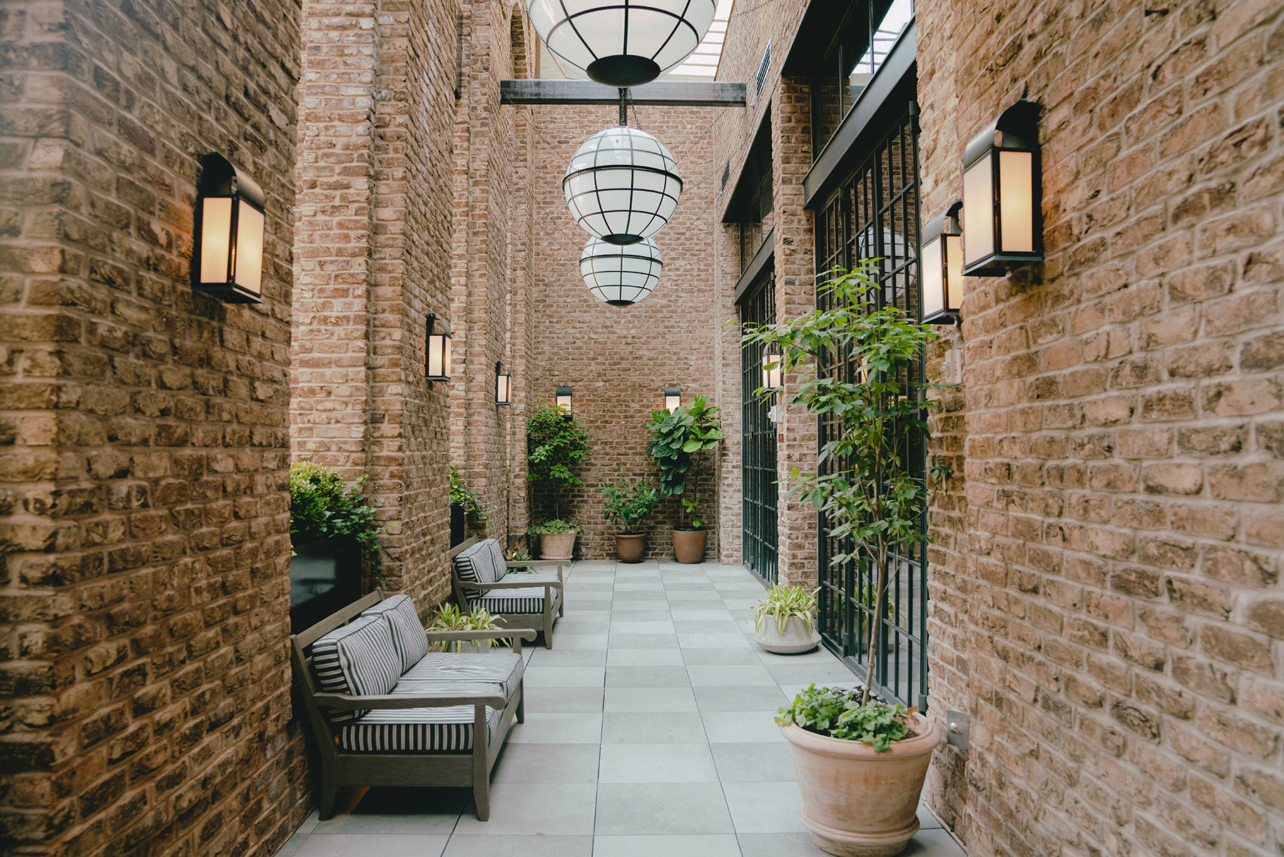 A cozy courtyard with brick walls, potted plants, and a seating area.