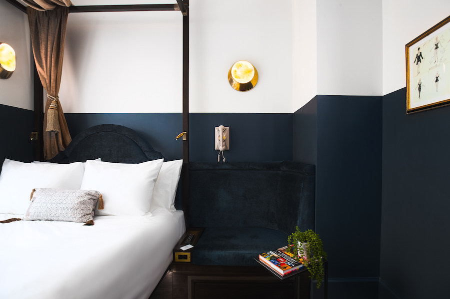 A hotel room with a bed, nightstand, and lamp.