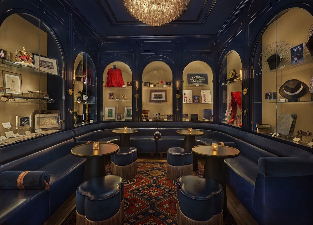 A luxurious lounge with blue leather banquette seating, arched shelving with decorative items, and a chandelier.