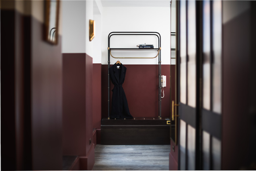 A hotel room with a coat rack and telephone