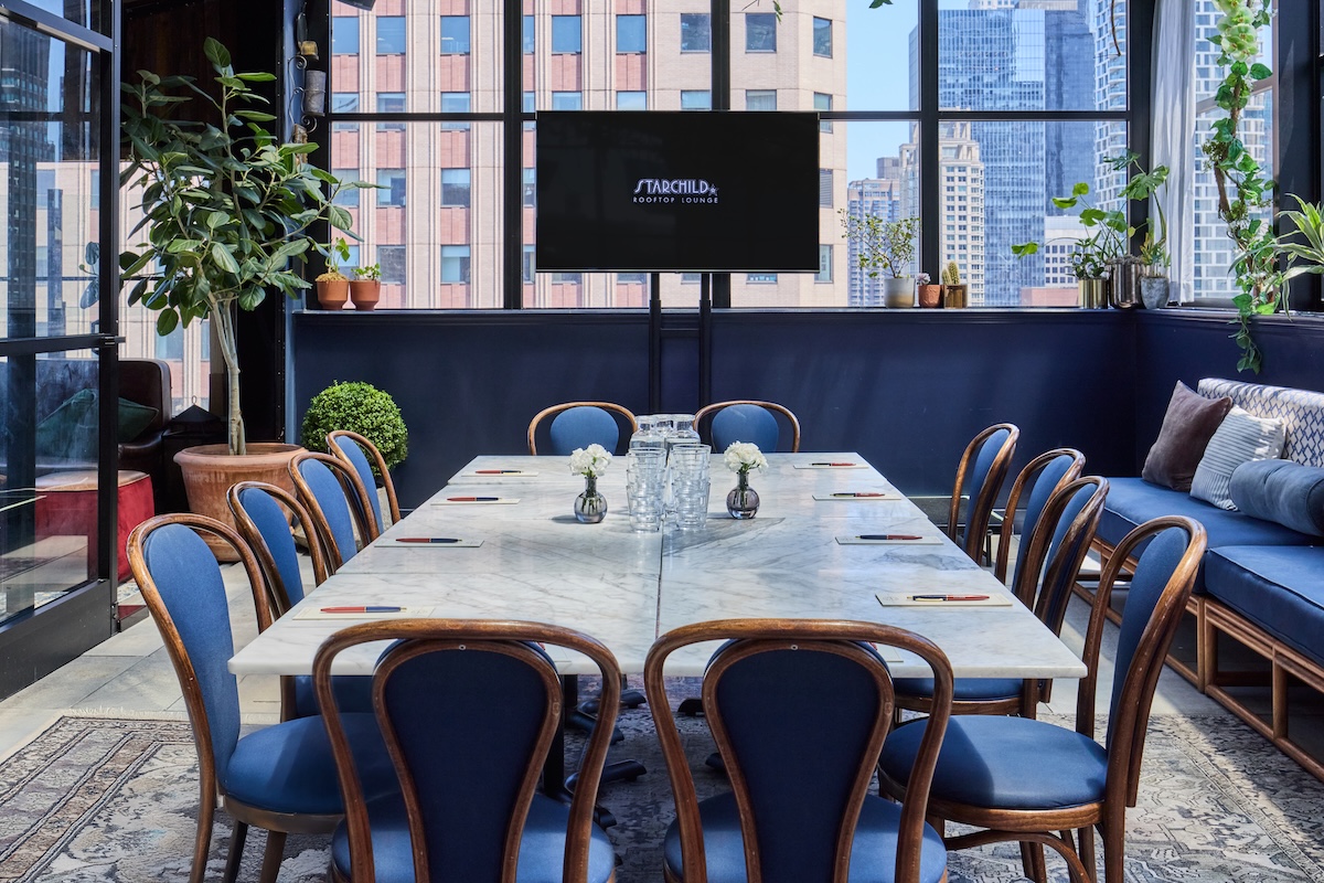 A meeting room with a large marble table, blue chairs, and a city view.