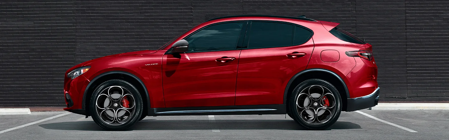 Side view of a parked red 2025 Alfa Romeo Stelvio in a parking lot