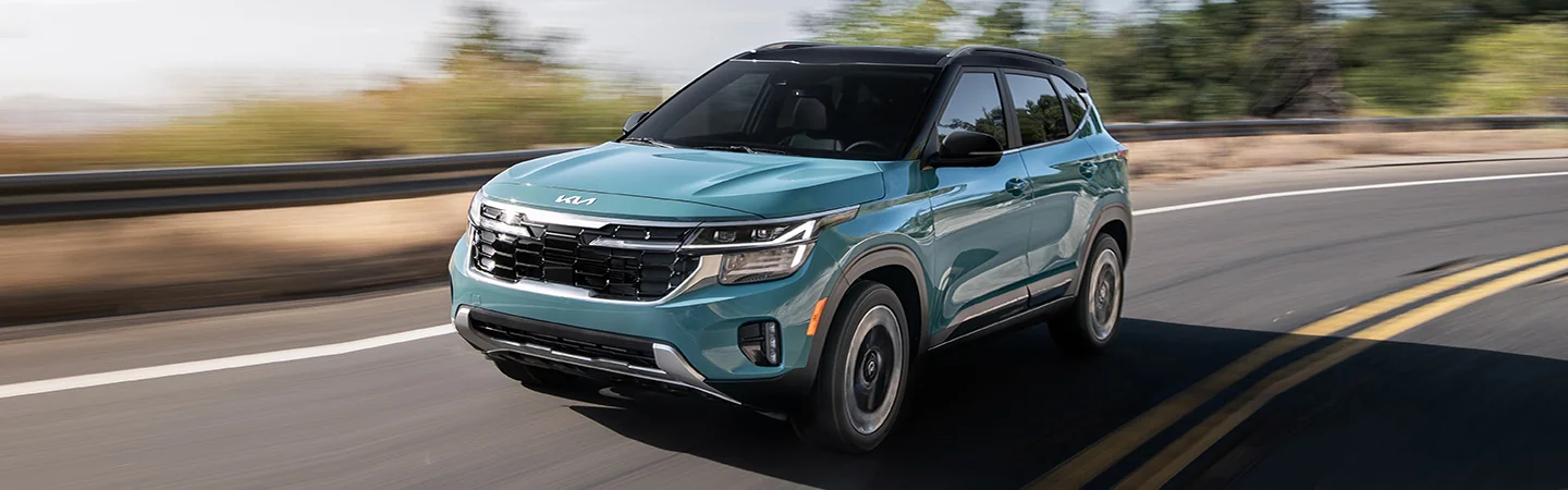 A teal 2025 Kia Seltos Denim driving on a road