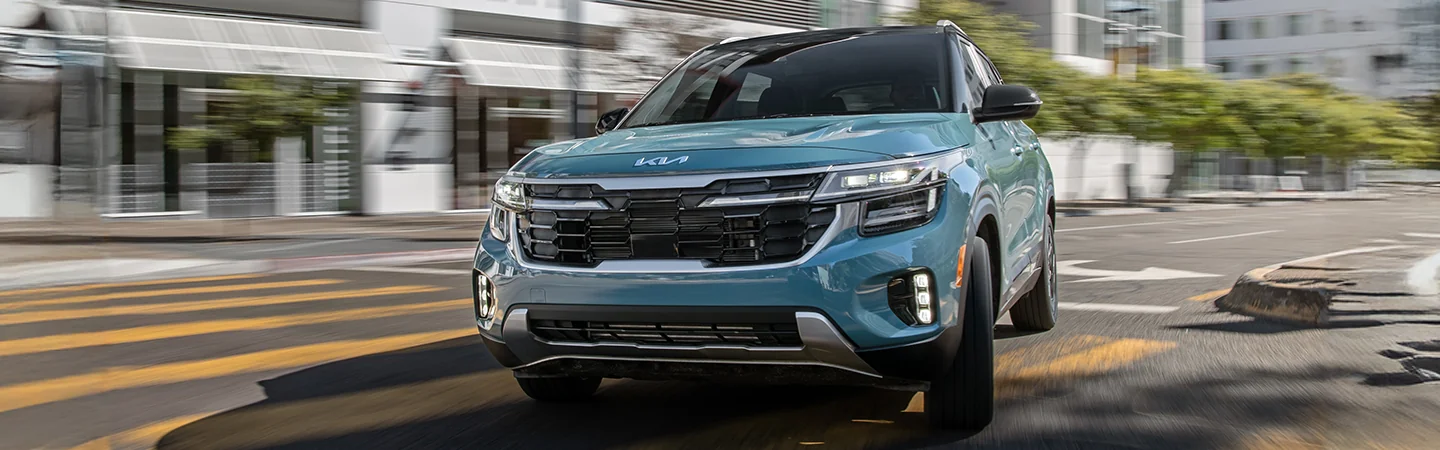 Front vuew of a blue 2025 Kia Seltos driving in the city