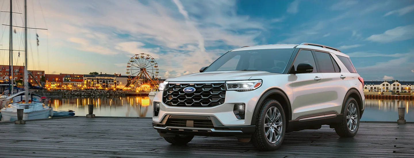 Front view of a parked gray 2026 Ford Explorer at a lake with a city in the background