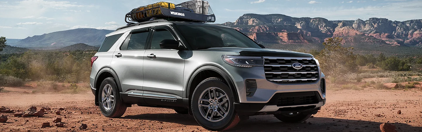 Side view of a parked gray 2026 Ford Explorer in the desert with mountains in the background