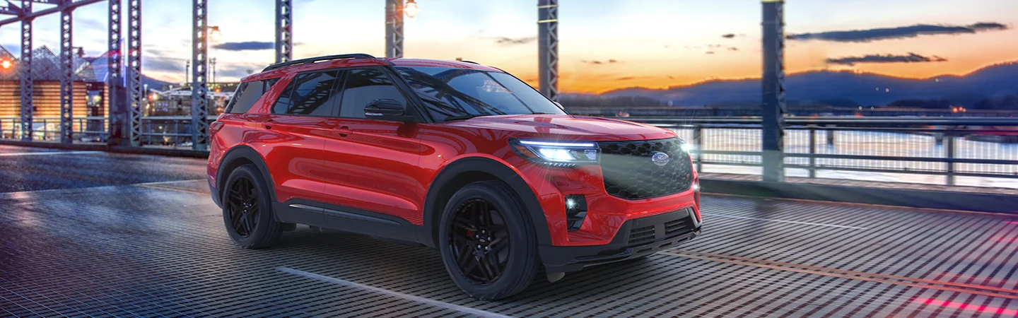 Side view of a red 2026 Ford Explorer driving over a city bridge