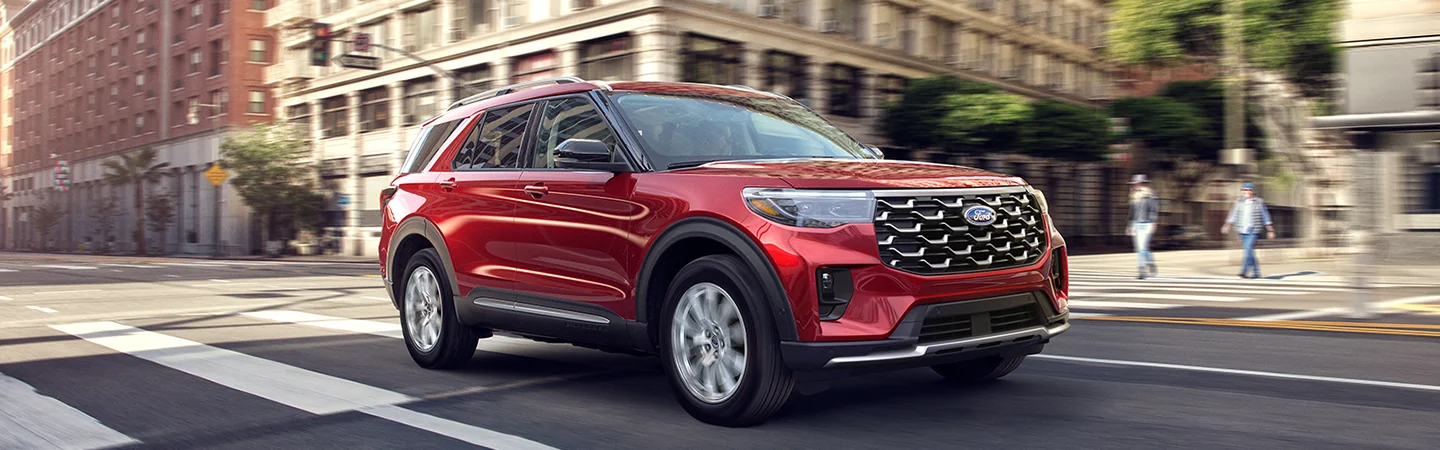 Front side view of a red 2026 Ford Explorer driving in the city
