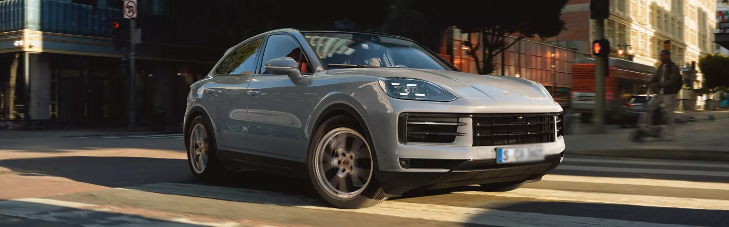 Front view of a 2026 Porsche Cayenne Coupe driving on a city street