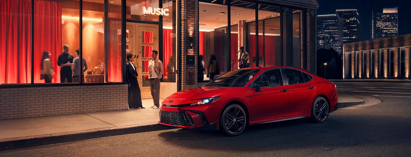 2026 Toyota Camry parked in front of a restaurant at night in the city