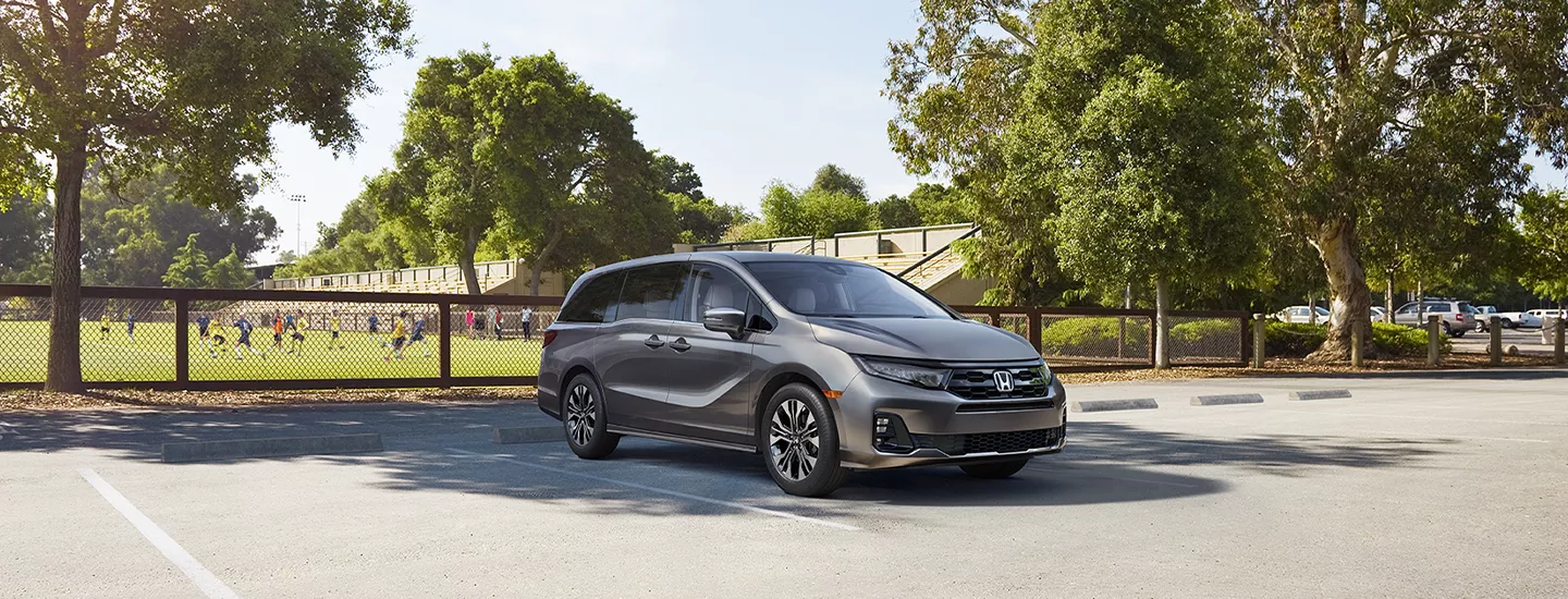 2026 Honda Odyssey parked in front of a soccer field with kids playing in the background