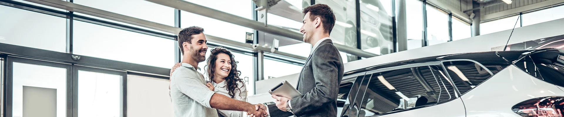 A couple shaking hands with car salesperson in showroom