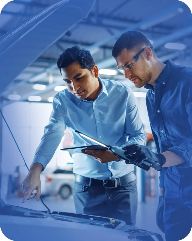 car mechanic and another person looking over open engine