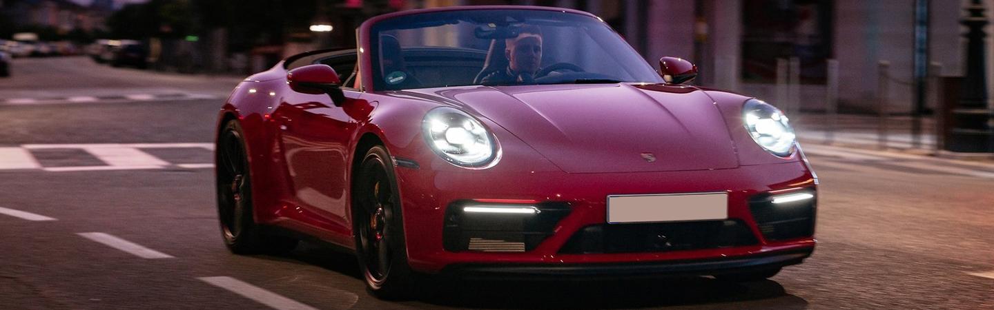 Front view of a red 2022 Porsche 911 Convertible driving in the city