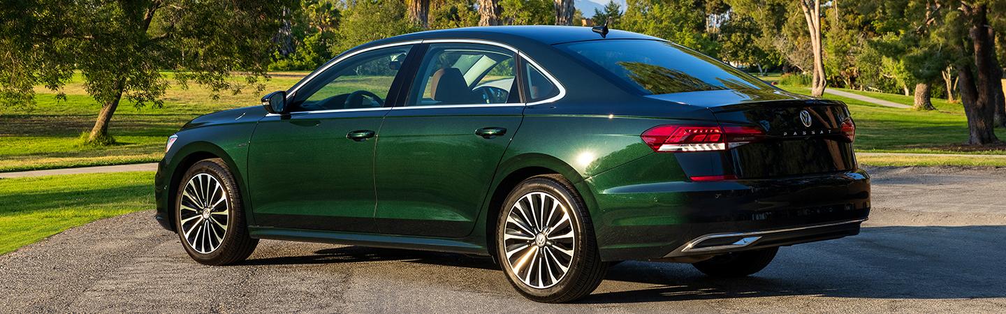 Side view of a green 2022 Volkswagen Passat parekd by some trees