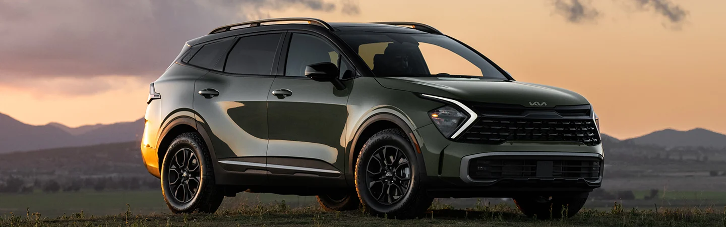 A parked 2025 Kia Sportage X-Pro Prestige with a sun set over the mountains in the background