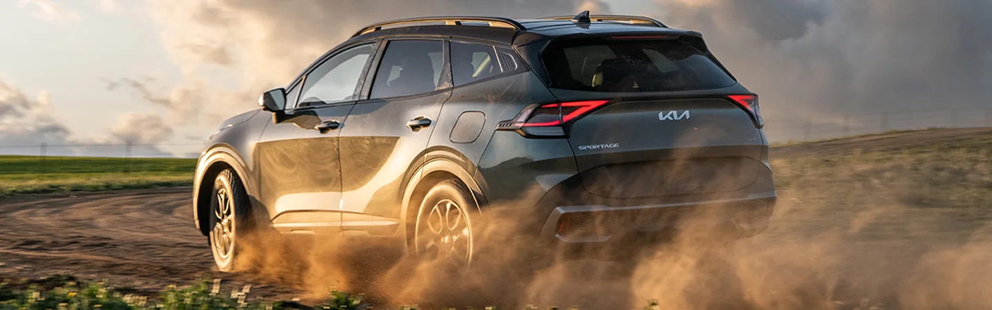 Back view of a 2025 Kia Sportage driving in the dirt