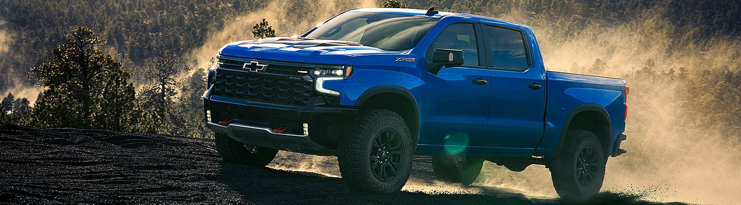 Blue Chevrolet Silverado 1500 driving up a dirt hill