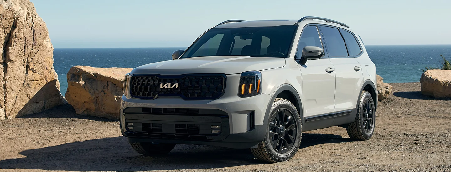 Front view of a gray 2025 Kia Telluride parked at a rocky ocean side spot