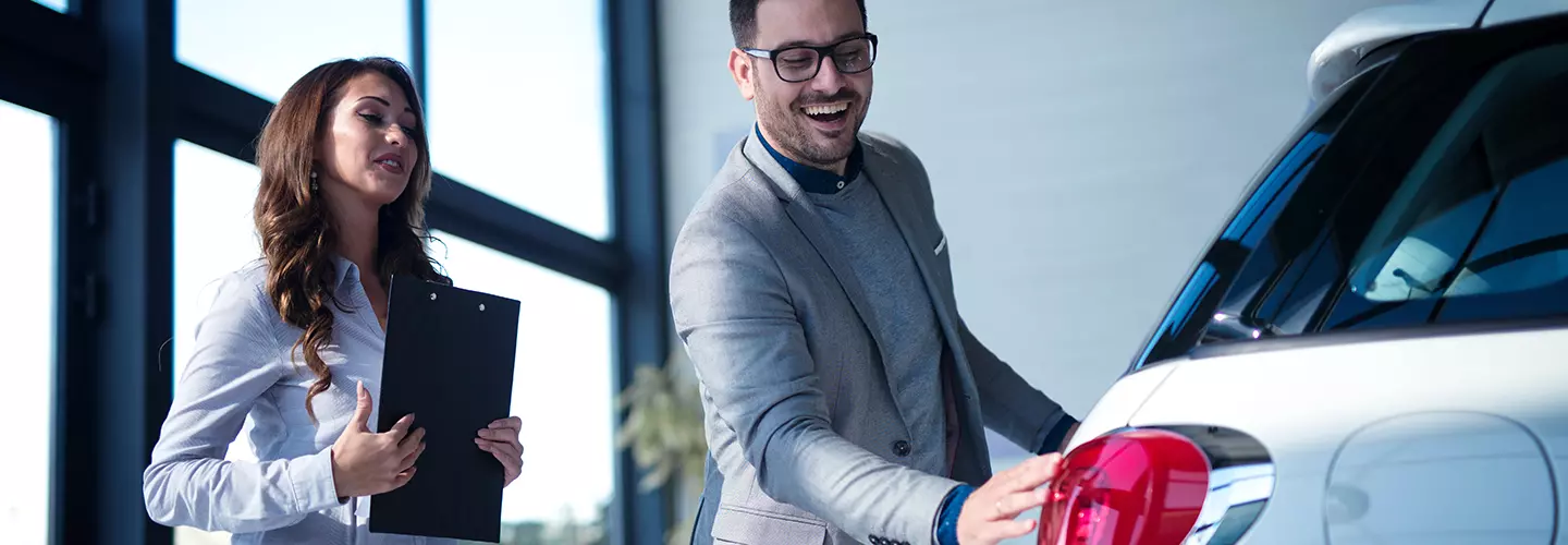 woman and man looking at a car with the man smiling