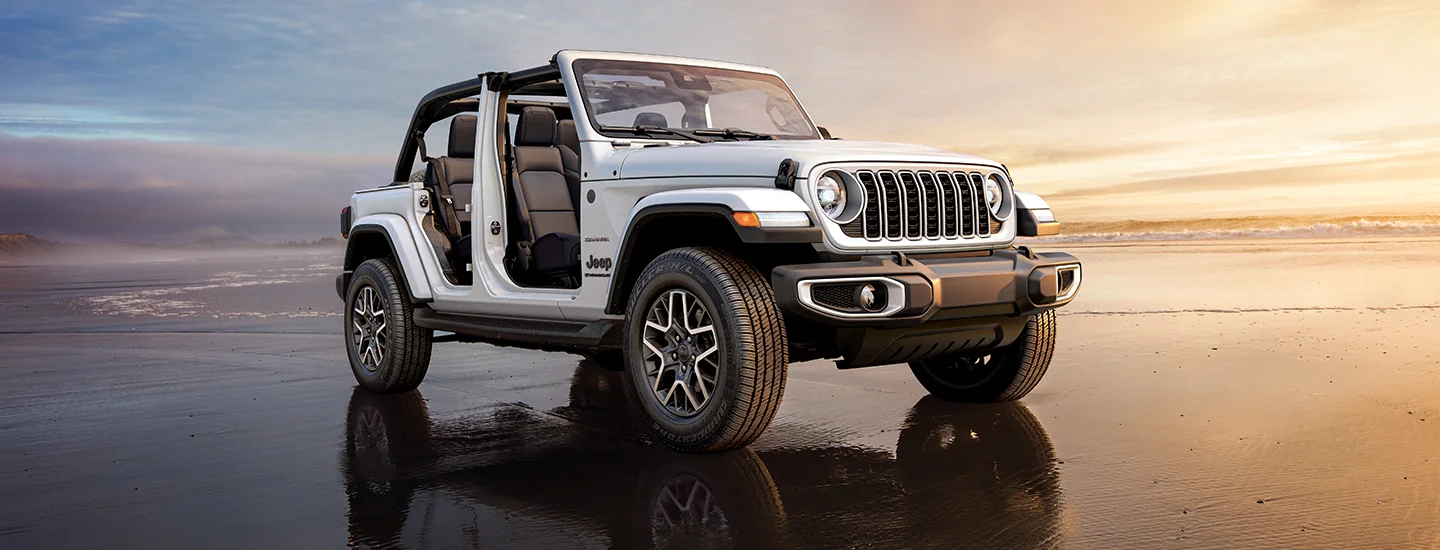 a white 2026 Jeep Wrangler Sport with all doors off drinv by the seashore on the beach