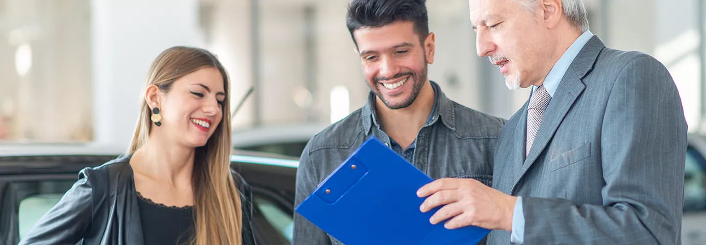 salesman showing a couple information on a clip board