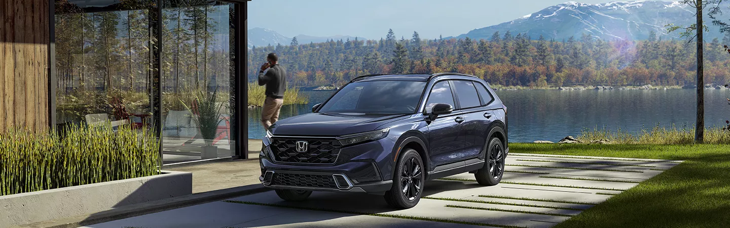 2026 Honda CR-V parked next to a lakeside residence near the mountains