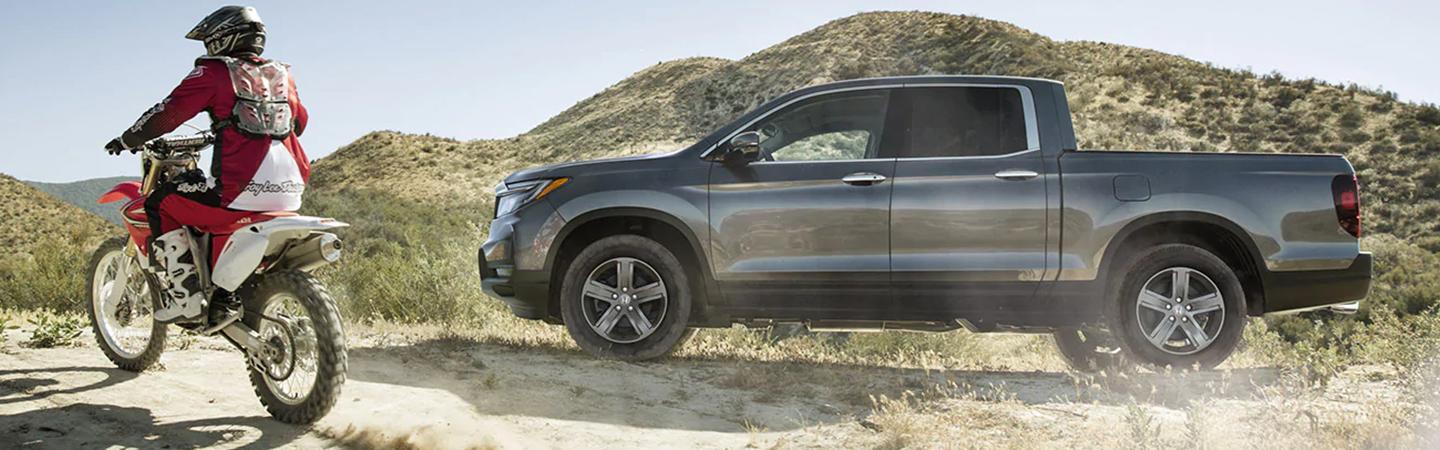 silver 2022 Honda Ridgeline parked off road with motorcycle going by