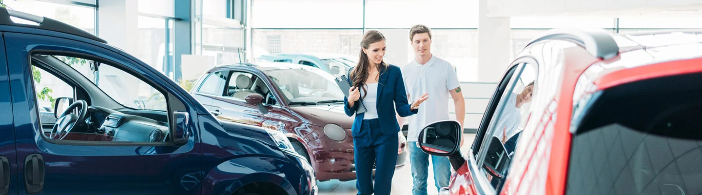 Sales person helping customer look at new cars