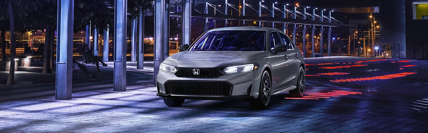 front view of a silver 2026 Honda Civic Sport Hybrid at night