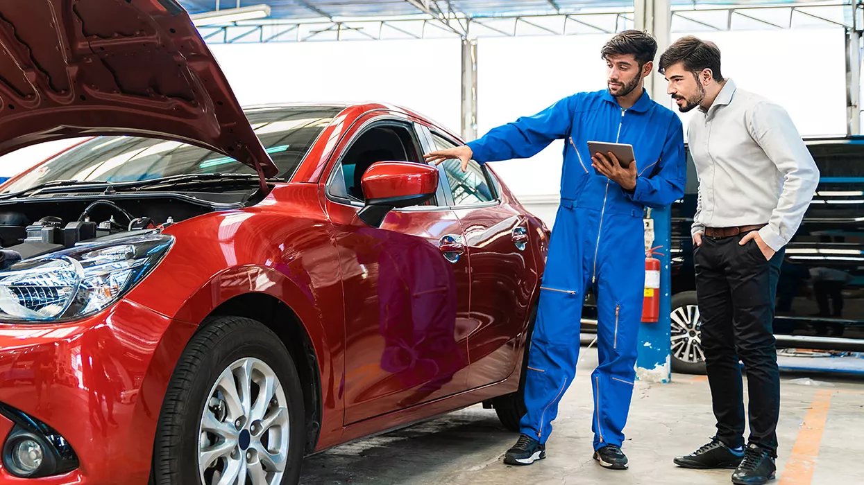 Mechanic talking to a car owner holding a tablet