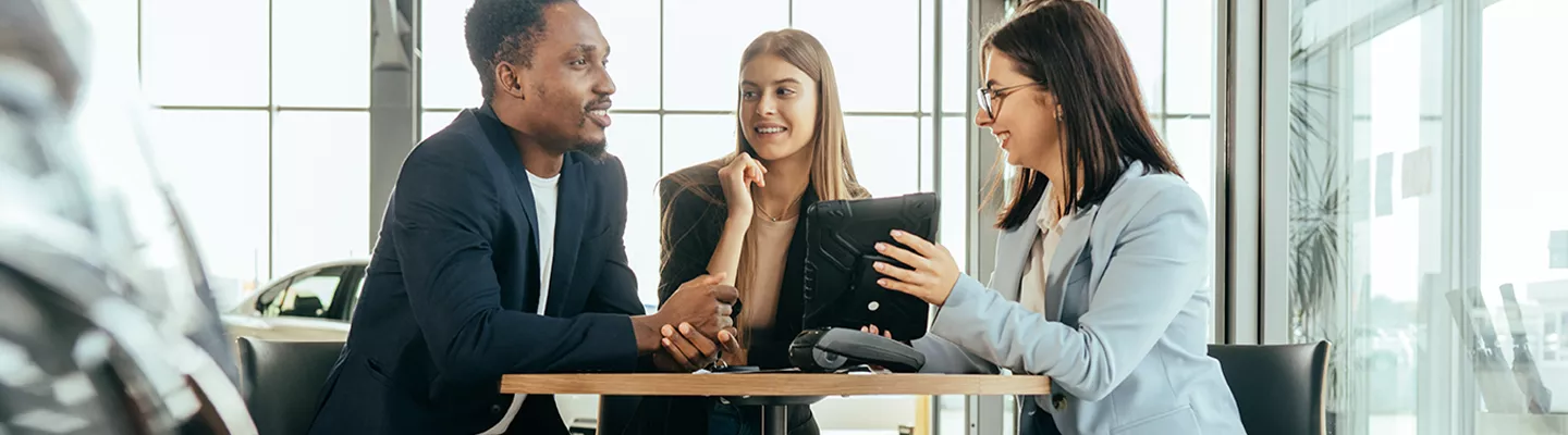 saleswoman showing man and woman information on a tablet
