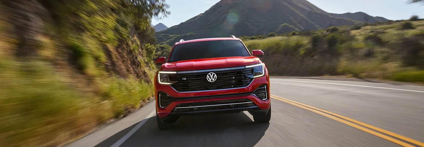 Frotn view of a red 2026 Volkswagen Atlas driving on a mountain road