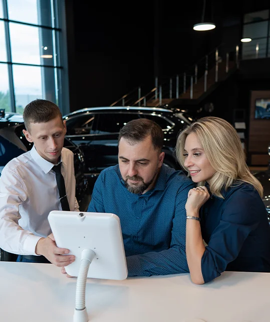 a couple looking over specifications of a car in the showroom