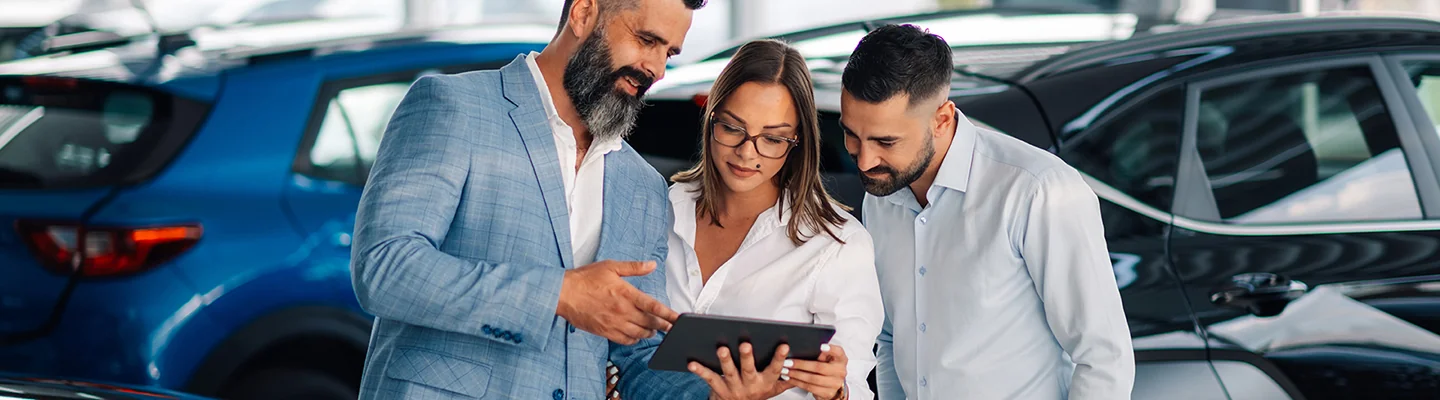 Sales person going over information about used cars with two customers