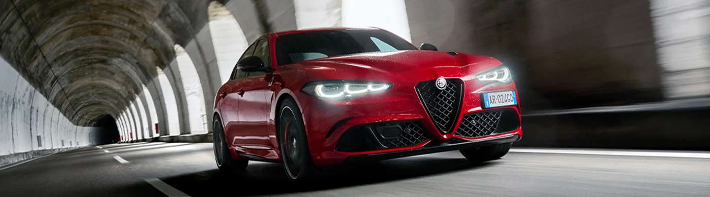 Front view of a red Alfa Romeo driving in a tunnel