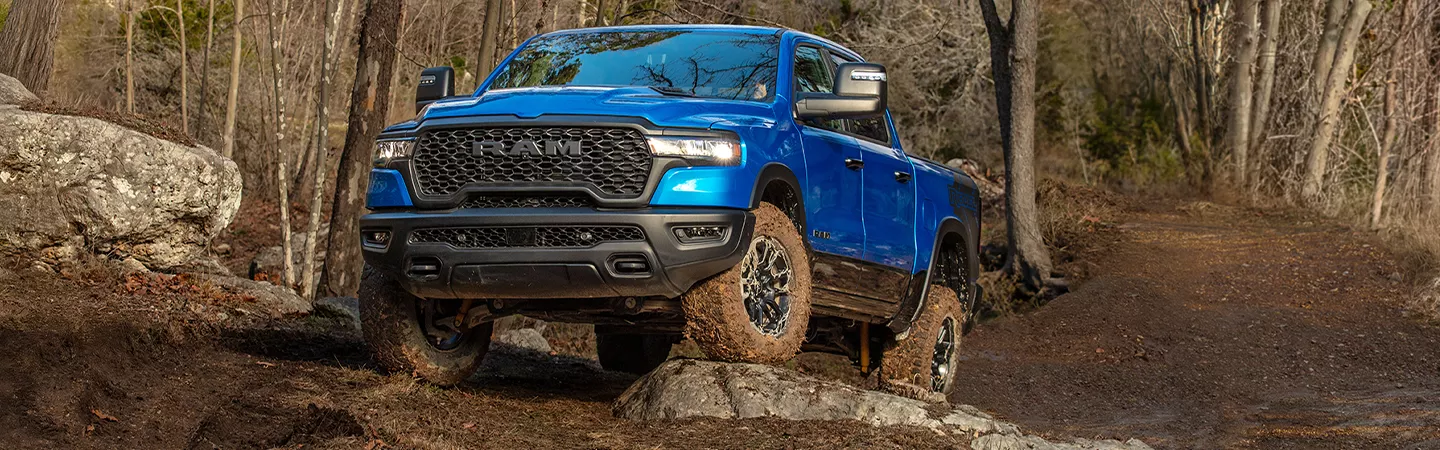 2026 RAM 1500 driving over rocks on a muddy trail