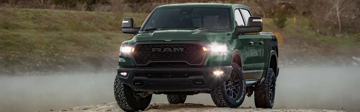 Front view of the 2026 RAM 1500 parked on a dirt road at dusk
