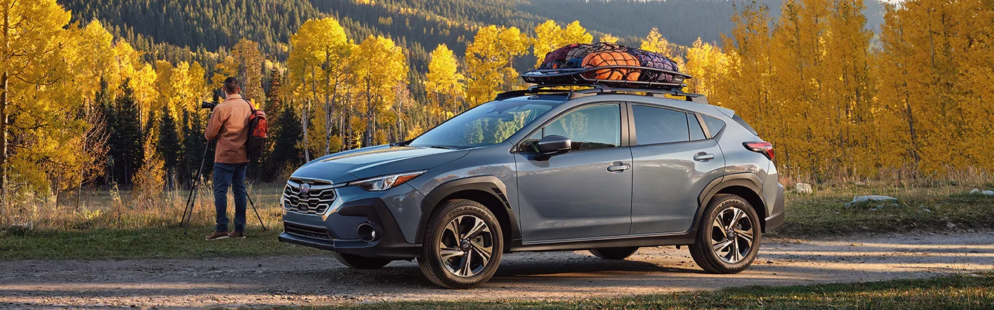 2025 Subaru Crosstrek driving on road with Fall leaves in the background in Waco, TX