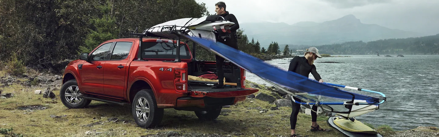 2023 Ford Ranger parked by a lake and 2 men unloading sailboards