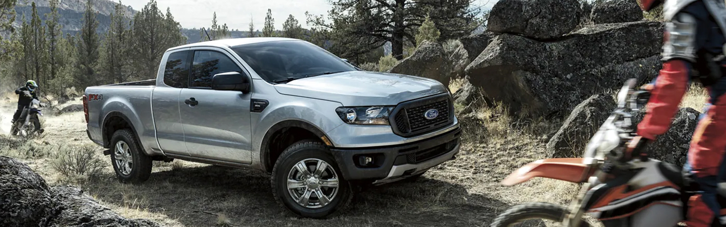 2023 Ford Ranger parked by rocky area with dirt bikes riding around