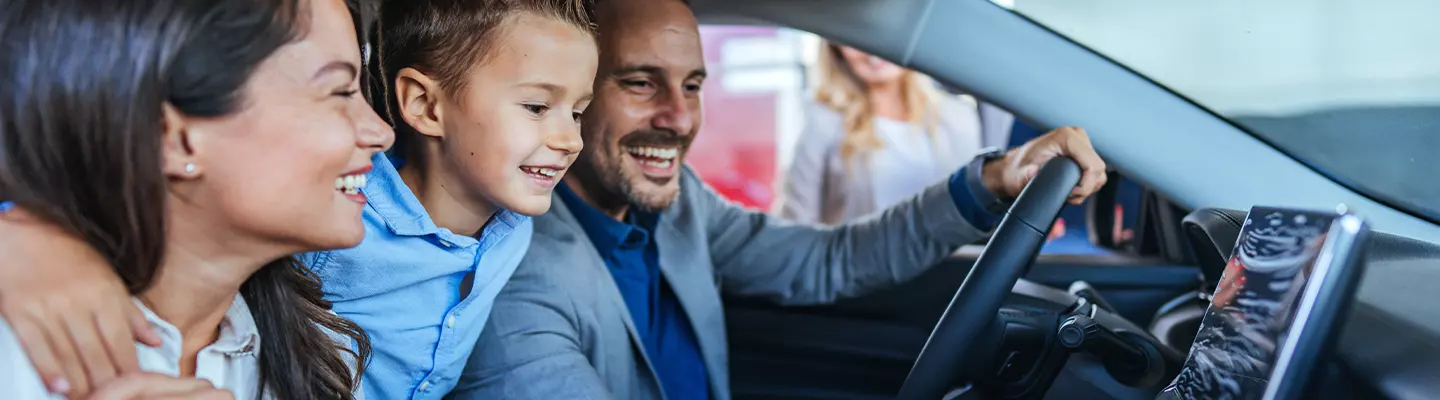 husband, wife and child smiling inside their new vehicle