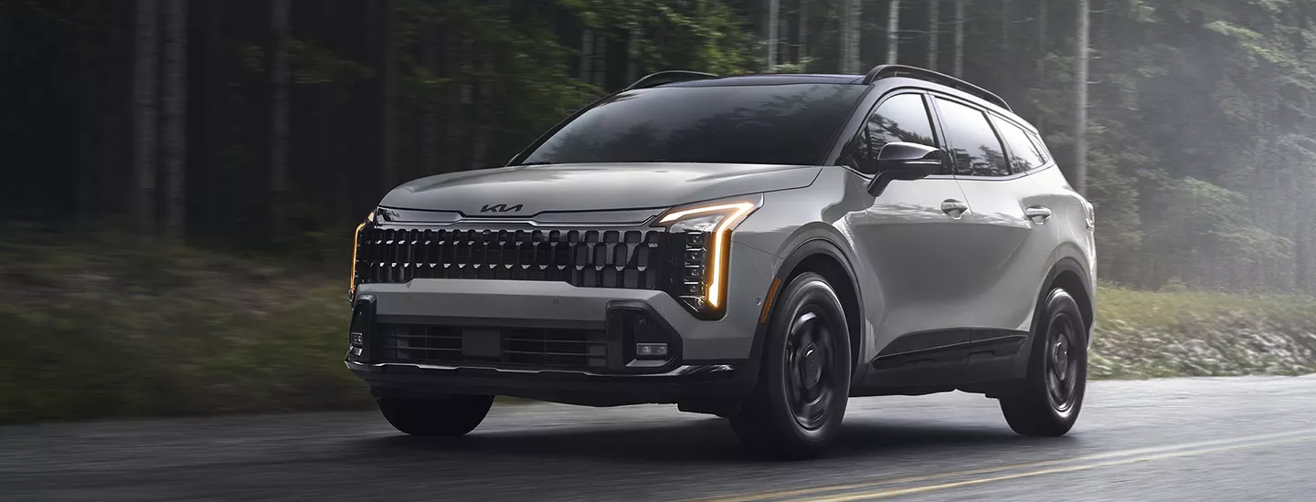 2026 Kia Sportage driving on a misty wooded road