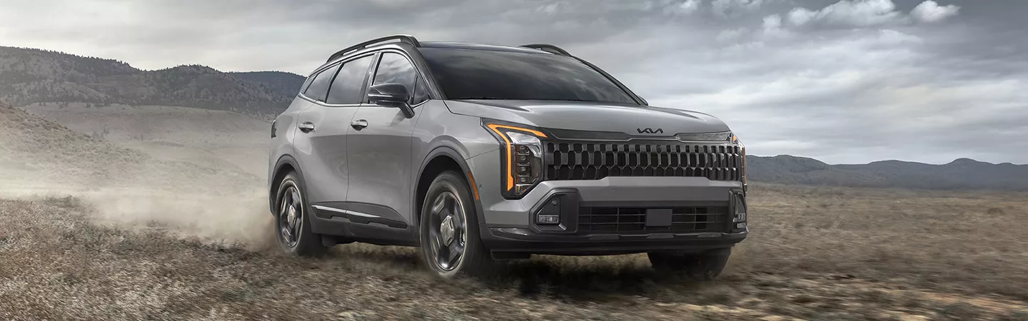 2026 Kia Sportage driving through the desert hills