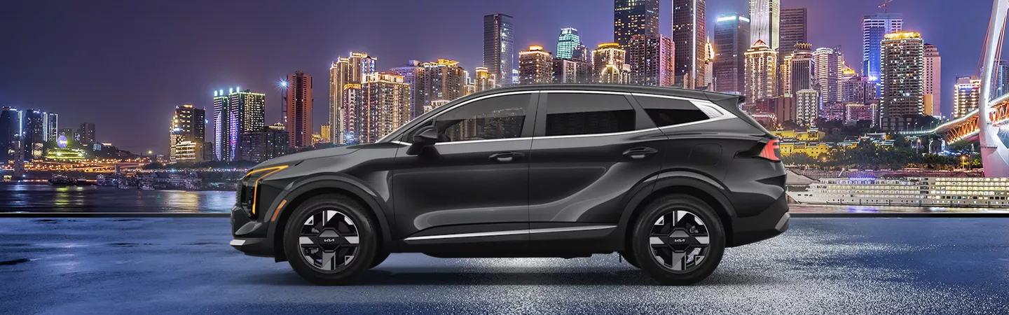 Side view of the 2026 Kia Sportage parked in front of a city skyline at night