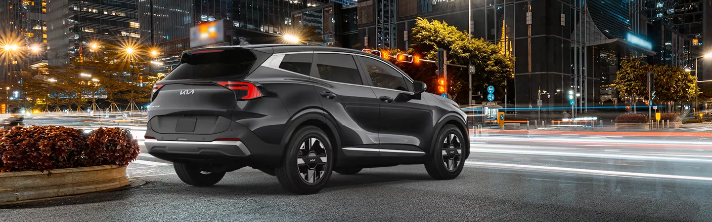 Rear view of the 2026 Kia Sportage driving through the city at night
