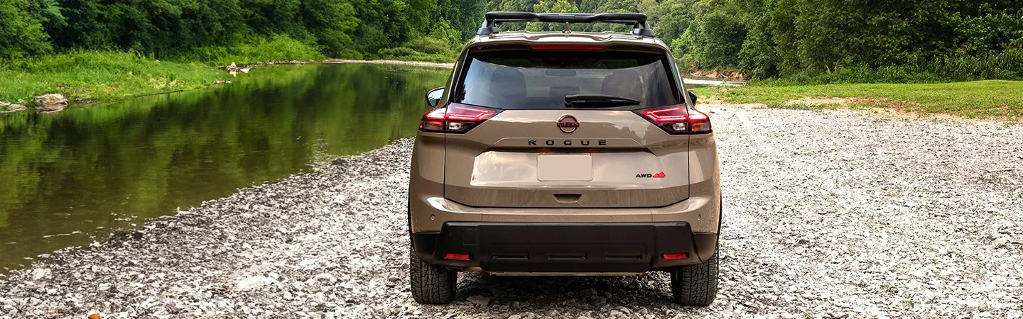 2026 Nissan Rogue parked next to a river with trees in the background