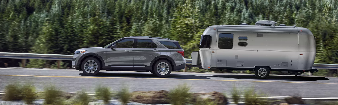 2026 Ford Explorer towing an Airstream camper in a wooded area